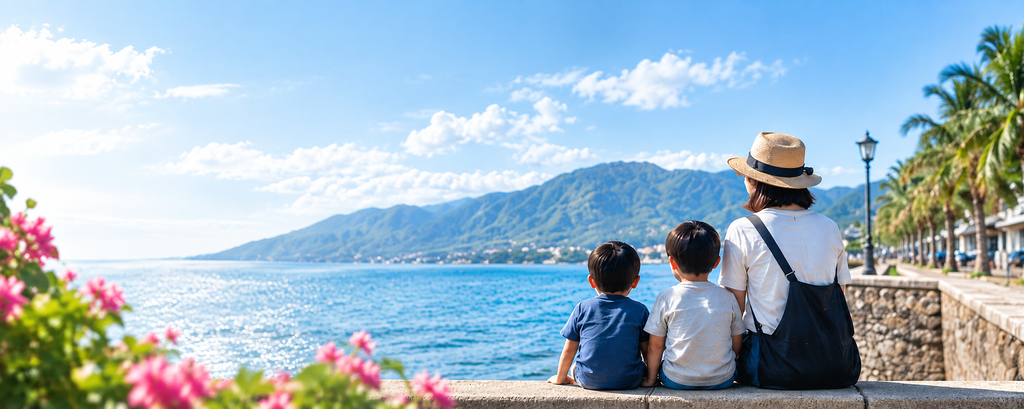 ドゥマゲッティの海辺で山と海を眺める母親と2人の子ども